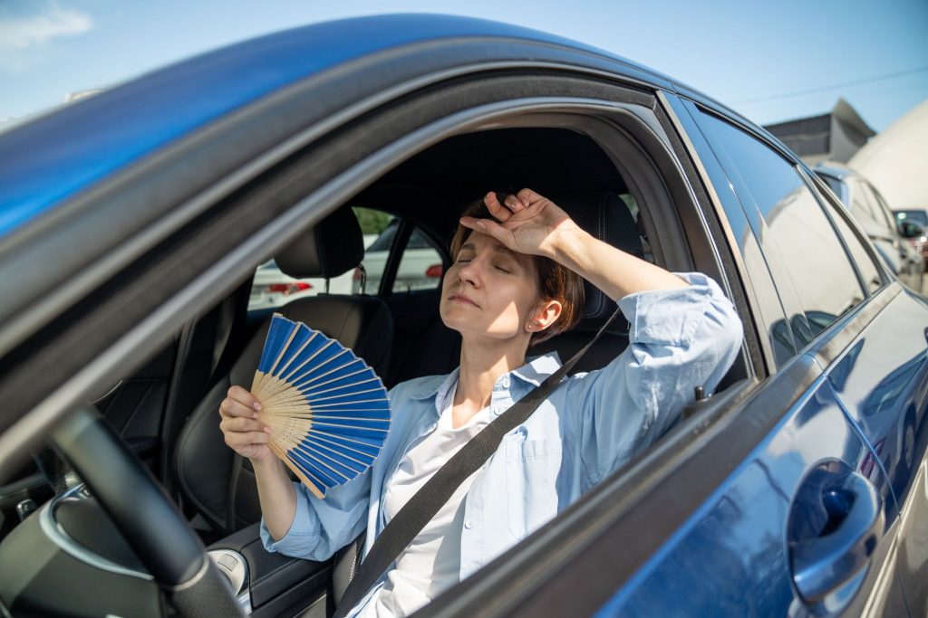 Hot Car A woman fanning herself off in a hot car.