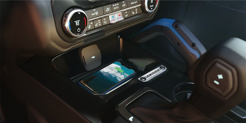Smartphone placed on a wireless charging pad inside a car's center console.